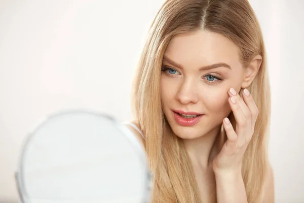 Cuidado facial de belleza. Chica con la piel sana mirando en el espejo —  Fotos de Stock