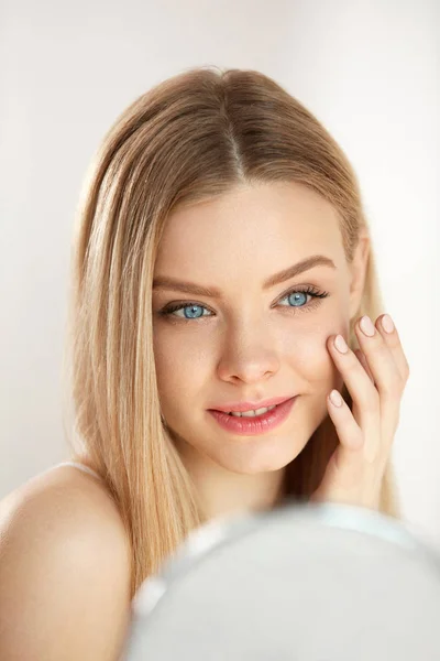 Hermosa mujer con maquillaje tocando la piel delante del espejo —  Fotos de Stock