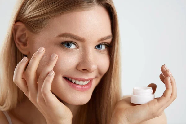 Cosméticos para la piel facial de mujer. Chica aplicando crema bajo los ojos — Foto de Stock