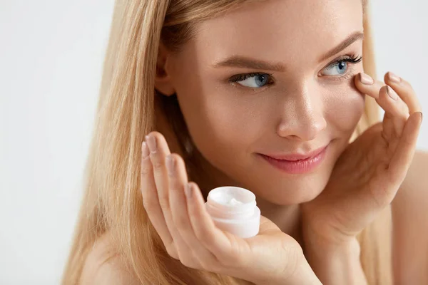 Hermosa mujer aplicando crema en la piel bajo los ojos — Foto de Stock