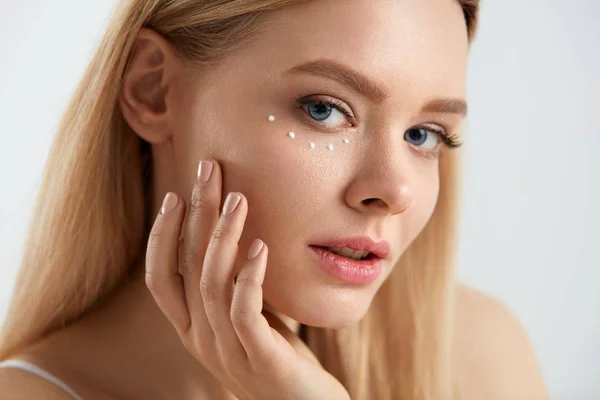 Cuidados faciais. Mulher com gotas de creme cosmético sob o olho — Fotografia de Stock