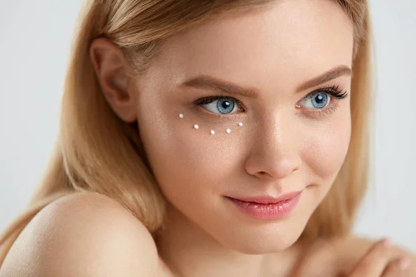 Beauty cosmetica. Vrouw met druppels oogcrème huid op huid — Stockfoto