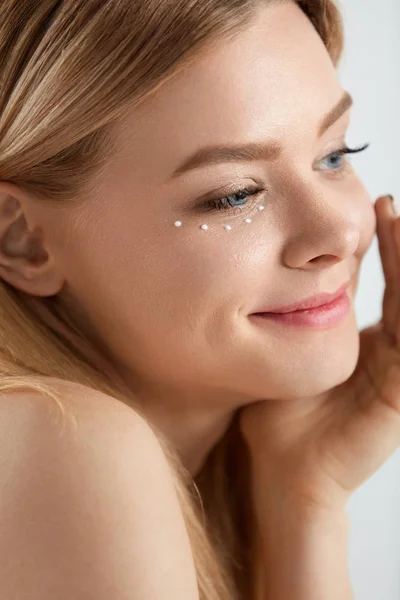 Cuidado facial. Mujer con gotas de crema cosmética bajo el ojo — Foto de Stock