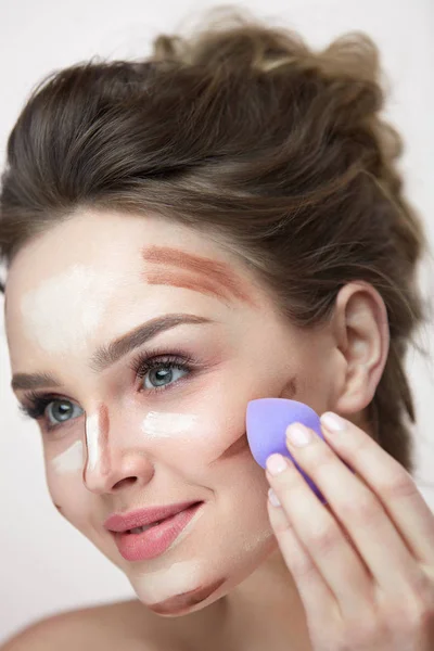 Belleza maquillaje facial. Hermosa hembra aplicando maquillaje con esponja — Foto de Stock