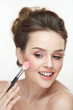 Kadın güzellik makyaj. Mutlu kadın cilt üzerinde pembe allık uygulayarak