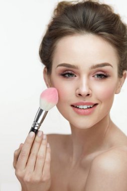 Kadın güzellik makyaj. Mutlu kadın cilt üzerinde pembe allık uygulayarak