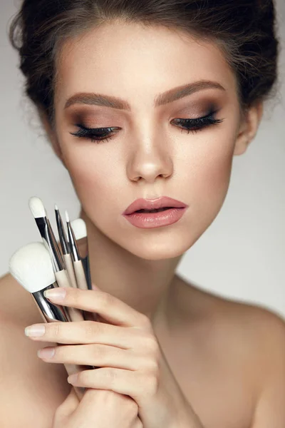 Mode kvinna porträtt. Flickan håller massa Makeup borstar — Stockfoto