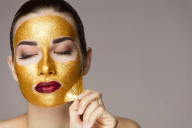 Güzellik ürünü. Seksi kadın altın maske kaldırma closeup 