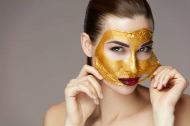 Güzellik kozmetik. Kadın yüzünden elleri ile gelen altın maske kaldırma
