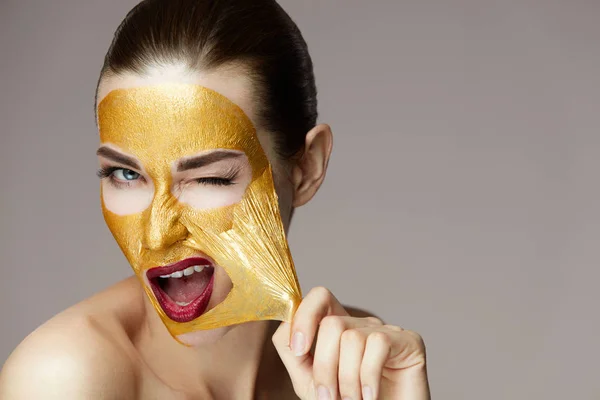 Krása žena tvář. Dívka opouštění kosmetické Zlatá maska z kůže — Stock fotografie