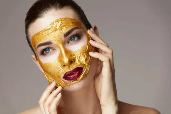 Facial Skin kozmetikumok. Női arany maszk simogatta arcát — Stock Fotó
