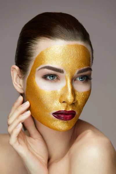 Cosmetisch Product. Mooi meisje met gouden masker gezicht aan te raken — Stockfoto