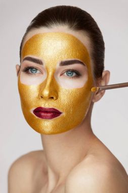 Yüz tedavi. Kozmetik altın maske yüzünde olan kadın