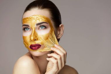 Güzellik ürünü. Seksi kadın altın maske kaldırma closeup 