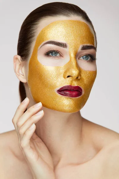 Produkt kosmetyczny. Piękna dziewczyna z Złota Maska dotykania twarzy — Zdjęcie stockowe