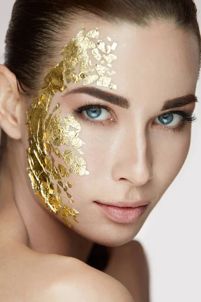 Beauty Woman Face. Mujer joven con máscara de oro en la piel suave — Foto de Stock