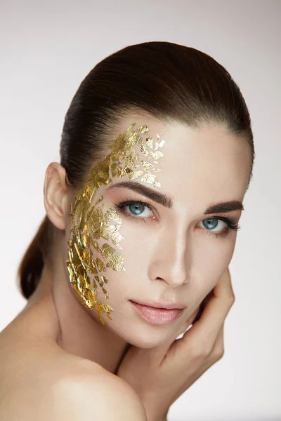 Cuidado de la piel de mujer. Mujer con máscara de oro tocando la piel facial — Foto de Stock