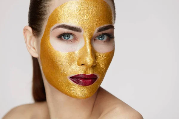 Beauty cosmetica. Jonge vrouw met gouden gezichtsmasker op zachte huid — Stockfoto