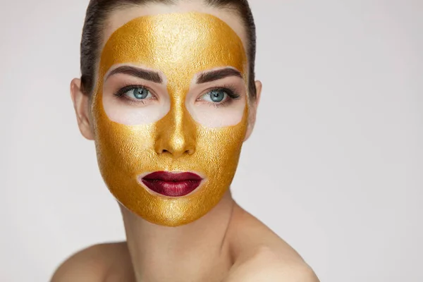 Cosméticos de belleza. Mujer joven con máscara de oro en la piel suave —  Fotos de Stock