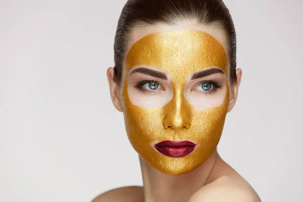 Cosméticos de belleza. Mujer joven con máscara de oro en la piel suave —  Fotos de Stock