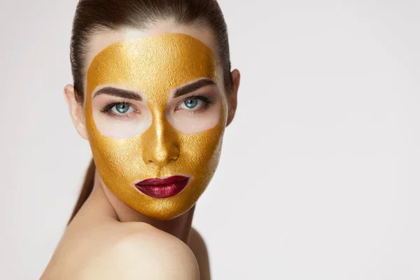 Schönheitskosmetik. junge Frau mit goldener Gesichtsmaske auf weicher Haut — Stockfoto