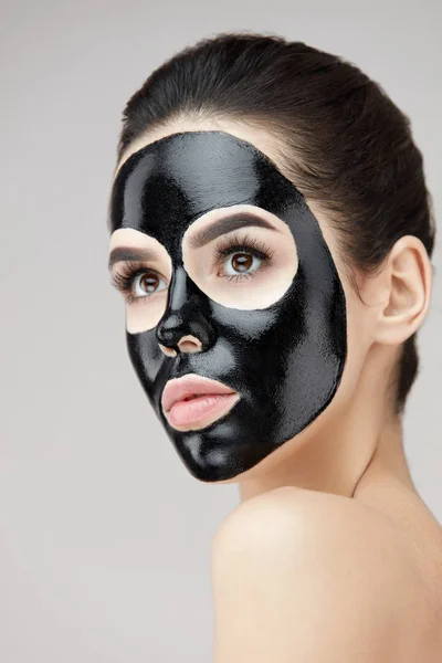 Mooie vrouw gezicht met cosmetische zwart masker op huid Peeling — Stockfoto