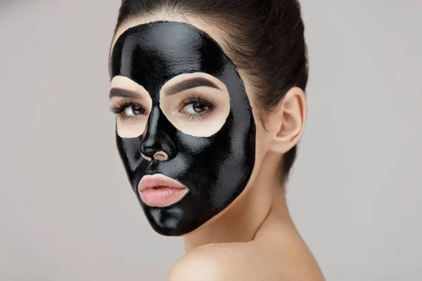 Mooie vrouw gezicht met cosmetische zwart masker op huid Peeling — Stockfoto