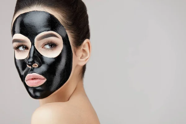 Mooie vrouw gezicht met cosmetische zwart masker op huid Peeling — Stockfoto