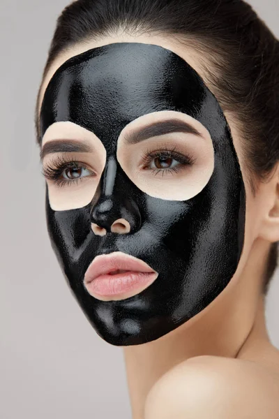 Hermosa cara de mujer con máscara de peeling negro cosmético en la piel — Foto de Stock