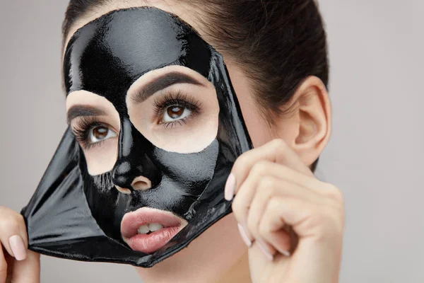 Kadın yüz bakımı. Güzel genç kadın siyah maske kaldırma — Stok fotoğraf
