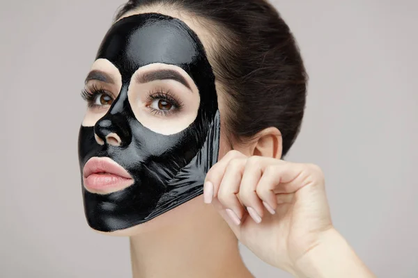 Soins du visage de femme. Belle jeune femme Enlever masque noir — Photo