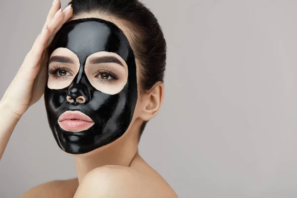 Vrouwelijke schoonheid gezicht huidbehandeling. Meisje met zwart masker Peeling — Stockfoto