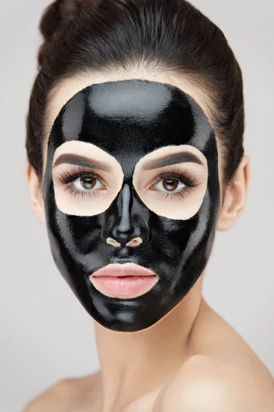 Cosmetología. Bella hembra con máscara de piel negra en la piel de la cara — Foto de Stock