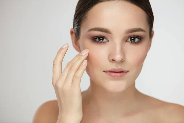 Cuidado cosmético de la cara. Mujer joven acariciando la piel facial —  Fotos de Stock