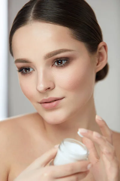 Gesichtspflege. Frau mit natürlichem Make-up hält Creme — Stockfoto