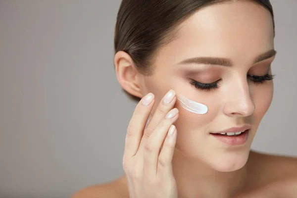 Soins de la peau beauté. Jeune femme avec maquillage naturel appliquant la crème — Photo