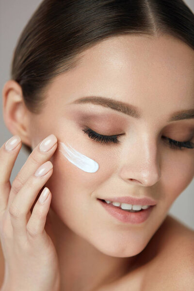 Facial Care. Closup Beautiful Woman Putting Skin Cream On Face