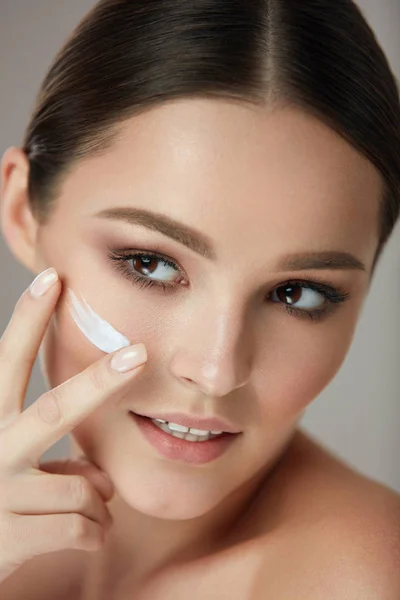 Hudvård för ansiktet. Closup vacker kvinna sätta hudkräm på ansikte — Stockfoto