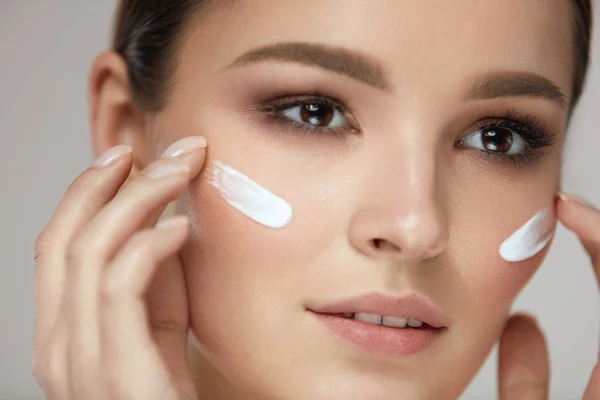 Krásná žena s čerstvým make-up použitím krém na obličej kosmetický — Stock fotografie