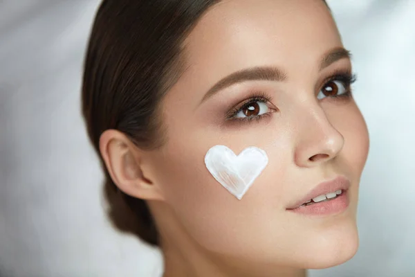 Woman Beauty Face Cosmetics. Female With Cream Heart On Skin