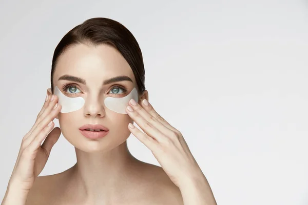 Cuidado de la piel de belleza facial. Mujer Aplicando Parches Bajo los Ojos en la Cara — Foto de Stock