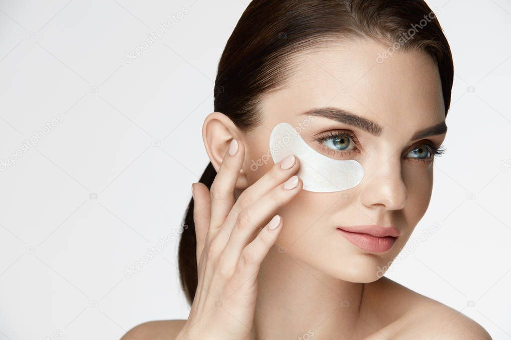 Eye Skin Care. Beautiful Smiling Female Applying Under Eye Mask