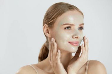 Kozmetik maskesi. Güzel gülümseyen kadın yüz maskesi uygulama