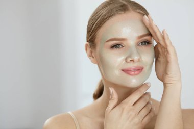 Kozmetik maskesi. Güzel gülümseyen kadın yüz maskesi uygulama