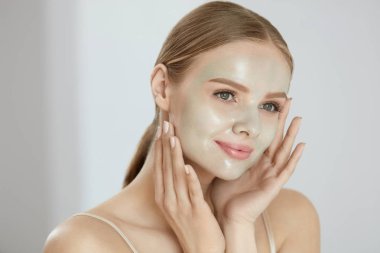 Kozmetik maskesi. Güzel gülümseyen kadın yüz maskesi uygulama