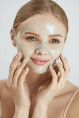 Kozmetik maskesi. Güzel gülümseyen kadın yüz maskesi uygulama