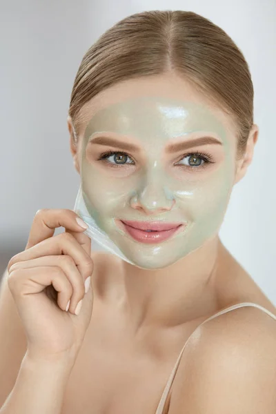 Ansiktsmask. Närbild vacker flicka att ta bort masken från huden — Stockfoto