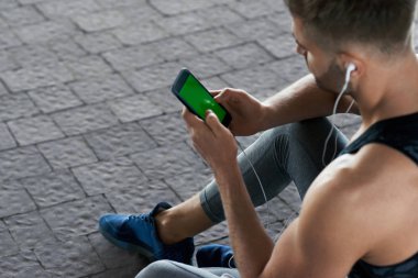 Adam açık havada egzersiz sonra telefonda müzik dinleme.