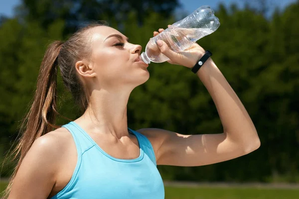 Frau trinkt Wasser nach dem Laufen. — Stockfoto