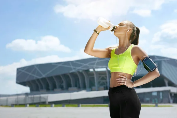 Bebe agua de la botella. Mujer bebiendo después de correr — Foto de Stock